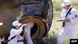 Các nhân viên thu nhặt một mẫu từ phi thuyền Thần Châu-9 sau khi phi thuyền đáp xuống