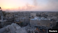 叙利亚反叛武装控制的阿勒颇的哈拉克附近,人们检查空袭带来的破坏。