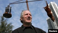 资料照:创作国殇之住的丹麦雕塑家高志活(Jens Galschiot)在香港维多利亚公园内树立的他的雕塑作品“疯牛病”前接受记者采访。(2005年12月15日)