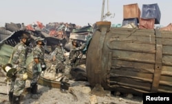 戴着防毒面具的防化兵在天津爆炸现场检查一个大罐子(2015年8月16日)