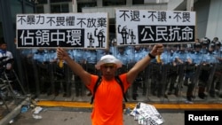 在香港政府机关门前,有防暴警察把守,示威者手持标语牌。(2014年9月27日)