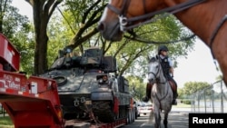 在首都华盛顿,一名美国国家公园骑警经过一辆布雷德利装甲步兵战车。(2019年7月3日)