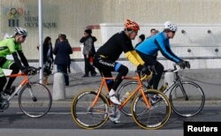 U.S. Secretary of State John Kerry, center, cycles past the Olympic Museum in Lausanne, France, March 16, 2015.