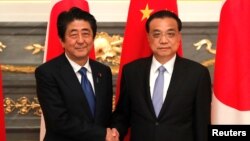 日本首相安倍晋三在东京与到访的中国总理李克强握手。(2018年5月9日)