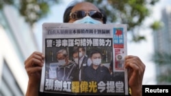 在香港法院审理壹传媒和苹果日报高管期间,一名支持者手举香港苹果日报站在法院外。(2021年6月19日)