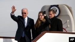 在北京国际机场,美国副总统拜登在孙女和儿子的陪伴下走下飞机,向迎候者挥手致意。(2013年12月4日)
