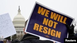 Seorang demonstran membawa poster berisi tulisan "Kami tidak akan mengundurkan diri" dalam aksi demo mendukung pegawai federal AS di depan Gedung Capitol, Washington, pada 11 Februari 2025. (Foto: Reuters/Craig Hudson)