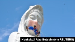 日本福岛的工人给57米高的观音菩萨雕像“带”上口罩,祈祷新冠疫情早日结束。(路透社)