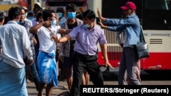 缅甸仰光,一名军方支持者用手里的锐器指着反政变示威者。(2021年2月25日)