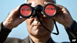 Một người đàn ông sử dụng ống nhòm để theo dõi giao tranh xảy ra tại Kobani từ một đỉnh đồi trên biên giới Syria - Thổ Nhĩ Kỳ.