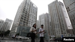 2021 年 7 月 13 日,人们走过中国北京中央商务区 (CBD) 的办公楼。