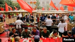 人们在新疆喀什老城区飘扬的中国国旗下吃饭 (2018年9月6日)