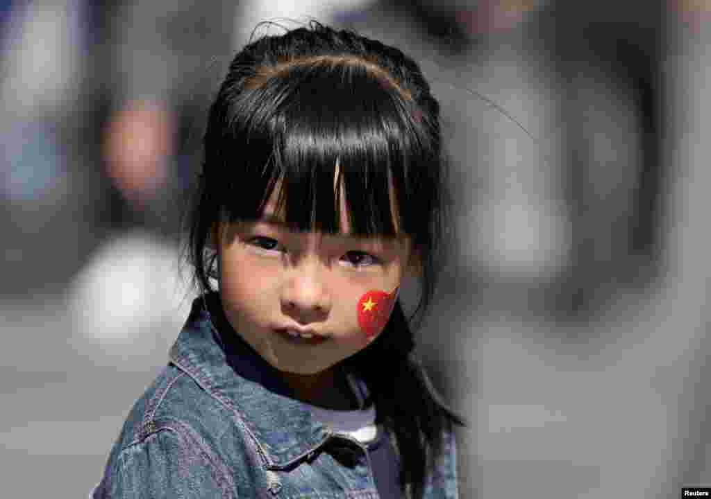 2018年10月1日,中华人民共和国的第69个国庆日,北京前门大街上。一个女孩的脸上贴着带有国旗图案的心形贴纸。