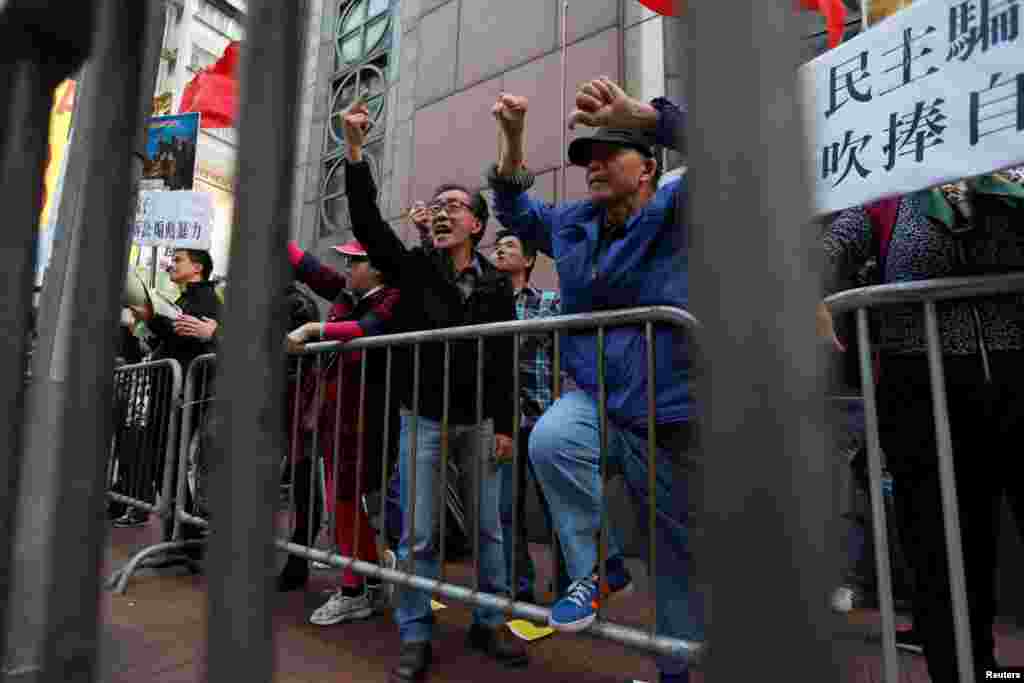 香港亲北京,反港独的示威者挑战那些争取民主的示威群众,举着标语牌:“民主骗子,吹捧自己”。两派之间有栅栏隔开(2017年1月1日)
