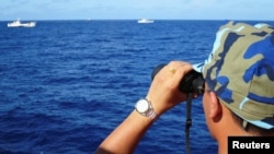 资料照：一名越南海警船成员在有争议的南中国海上观察中国海警船。（2014年7月15日）