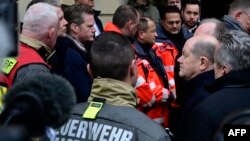 German Chancellor Olaf Scholz (R) talks to rescuers during a visit to the site of a car-ramming attack on a Christmas market in Magdeburg, eastern Germany, on December 21, 2024, resulting in several deaths and dozens of injured.
