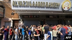 2023 年 10 月 15 日,在以色列对加沙地带南部汗尤尼斯的袭击中,流离失所的巴勒斯坦人排队领取面包。