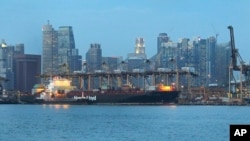 货轮开进新加坡港口,背景是新加坡金融区大楼。