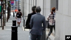 三名被控在入学考试中串谋作弊的中国公民在匹兹堡的联邦法庭过堂后为躲避摄影师而跑回法院。(2015年6月17日)