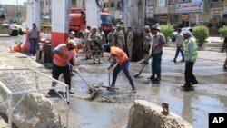 Công nhân dọn dẹp các mảnh vỡ sau một đánh bom ở phía bắc Baghdad, ngày 30/5/2016.