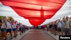 在波兰比亚里斯托克,人们游行举着一面巨大的历史悠久的白俄罗斯国旗表达与白俄罗斯人民团结一致。(2020年8月20日)