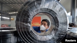 贵州省贵阳市一名戴着口罩的工人在缆线生产线上工作。（2020年2月25日）