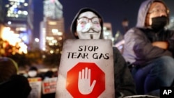 一名香港示威者手举标语牌抗议港警使用催泪弹。(2019年12月6日)