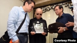 刘晓波遗孀刘霞手捧遗像。刘晓波弟弟刘晓瑄(右)和刘霞弟弟刘晖陪伴(沈阳市政府公布图片)