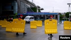 武汉开城第一天,武汉火车站前工人搬走为防疫设置的路障。(2020年3月28日)