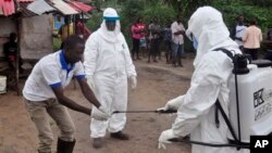 Nhân viên y tế sát khuẩn sau khi lấy mẫu máu kiểm tra ở khu vực mà cậu bé 17 tuổi đã chết vì Ebola tại Liberia hôm 30/6/2015.