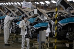 工人们佩戴口罩在位于湖北省武汉市的汽车装配线上工作。(2020年4月8日)