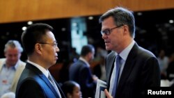 美国驻WTO大使习达难(右)在瑞士日内瓦举行的世界贸易组织(WTO)会议上与中国驻WTO大使张向晨交谈。(2018年7月26日)