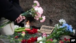 一名妇女在俄罗斯圣彼得堡的一处纪念碑前向阿列克谢·纳瓦尔尼献花致敬。(2024年2月21日)