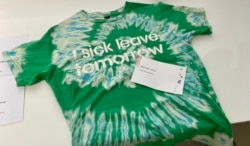 香港市民Phoenix 在反送中运动两周年义卖活动,以物易物方式带走一件喻意饮水思源的T恤。 (美国之音 汤惠芸拍摄)