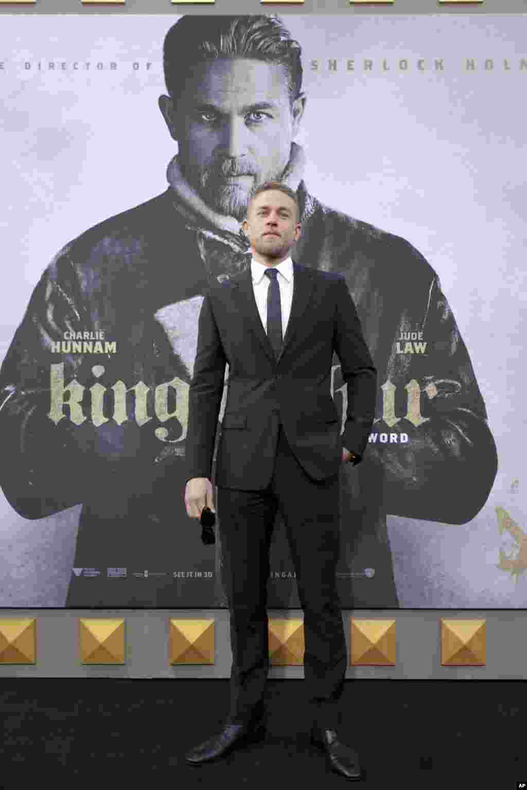 在电影《亚瑟王:斗兽争霸》( "King Arthur: Legend of the Sword" )的世界首映式上,主演亚瑟王的查理·汉纳在影片的海报前(2017年5月8日)。导演盖·里奇说:“我原来不确定查理是正确人选,是查理硬闯进我家,坚持说这个角色非他莫属。”汉纳说:“我们坐下来喝茶,2个小时后,我们又说又笑,扭打在一起。然后他说,你来试镜吧。我去试镜后,他就把这个角色给了我,开心的结局。”
