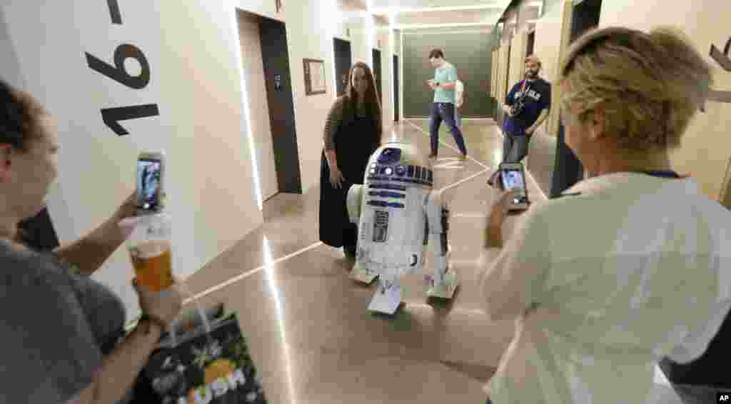 在西雅图的一座大楼里,影片《星球大战》里的机器人R2D2 和工作人员互动(2017年5月4日)。在6月下旬的拍卖中,这个机器人可能卖到200万美元。《星球大战》的一些道具也会拍卖,男主角用过的光剑可能卖到15万到25万美元。