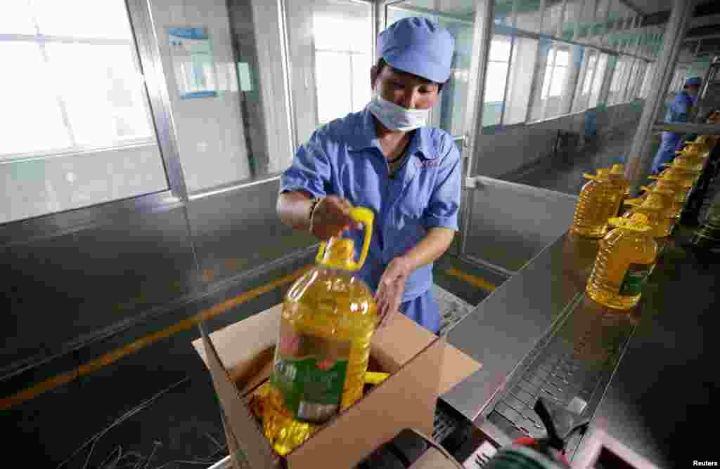 2018年7月4日,在中国山东省曲阜市,在粮油工业和进出口公司的工厂,工人把瓶装豆油装箱,这些豆油是用美国大豆提炼的。7月6日, 美国宣布对价值340亿美元的中国产品加征关税,中国随即对同等价值的美国产品加税,其中包括大豆。此前,中国市场上80%的大豆来自美国,大约有60%的美国大豆出口到中国,中国是美国大豆最大的市场。中国市场上豆粕价格的上涨引发对食品价格上涨的担忧。豆粕是大豆榨油后的渣,是猪饲料的重要原料,而中国是世界上最大的猪肉消费国。  