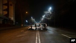 A police bus, which was burned after clashes, remains in an empty street in Almaty, Kazakhstan, late Saturday, Jan. 8, 2022.