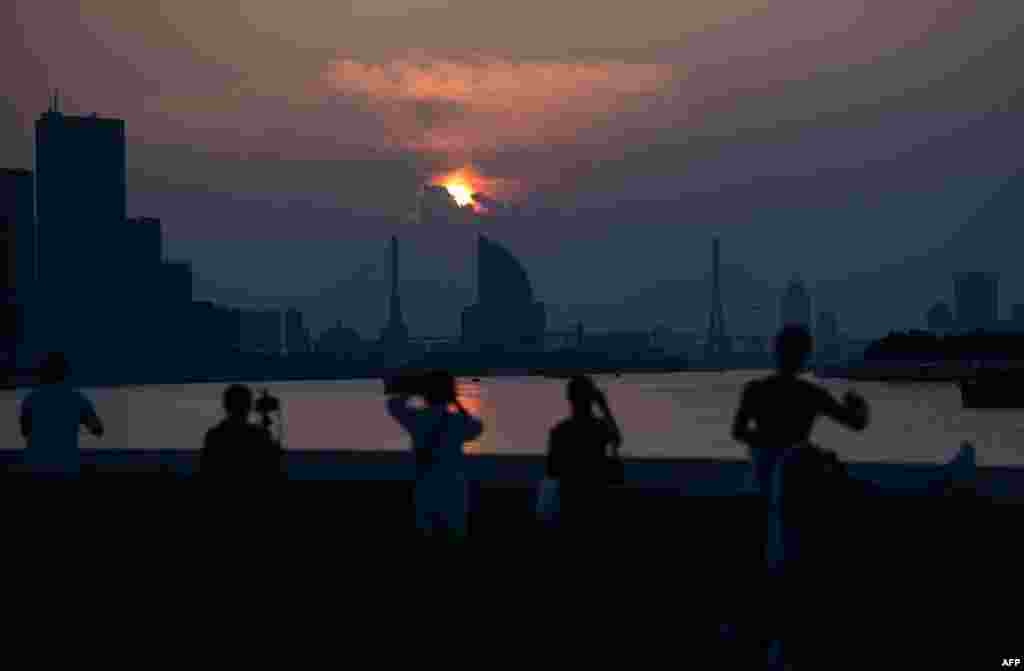 2018年8月8日,人们在上海黄浦江边观看太阳升起。