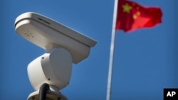 一面中国国旗在监控北京十字路口的海康威视安全摄像头附近飘扬。(2019年10月8日)