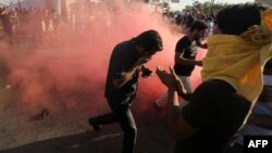 Những người ủng hộ giáo sĩ Iraq Moqtada al-Sadr chạy trốn khỏi đạn hơi cay của các lực lượng an ninh trong cuộc đụng độ sau khi những người biểu tình tràn vào Khu vực Xanh của Baghdad, ngày 20 tháng 5 năm 2016.
