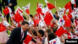 习近平访问韩国时在首尔的欢迎仪式上,儿童们挥舞中国和韩国国旗。