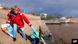 志愿者梅瑞迪斯和她七岁的儿子从洛杉矶附近的圣莫妮卡海滩收捡塑料瓶(资料照)