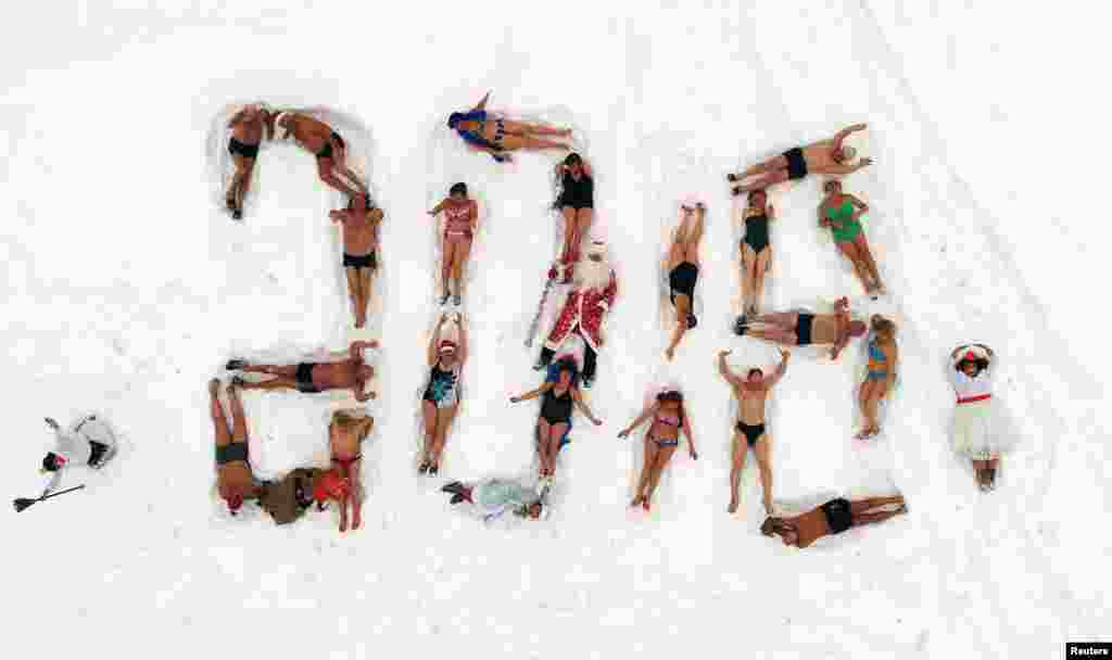 在俄罗斯西伯利亚城市克拉斯诺亚尔斯克的叶尼塞河河岸上，冬眠游泳俱乐部的成员们躺在雪地上组成了&ldquo;2018&rdquo;，迎接新年和圣诞节。他们多数人穿着泳装，也有人装扮成俄罗斯圣诞老人和白雪少女（2017年12月24日）。