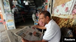 A Palestinian man reads a newspaper outside his store in Gaza City September 19, 2016.