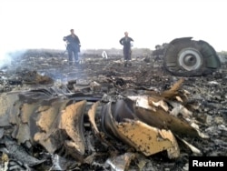 大图:乌克兰政府工作人员在飞机出事地点—乌克兰顿涅茨克附近的一个村庄—了解情况。