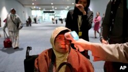 印度尼西亚国际机场工作人员1月22日对入境旅客进行体温检查。