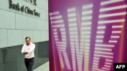 资料照 - 一位白领人士走过中国银行(香港)贴有“RMB" (人民币)字样的招贴画。照片摄于2011年9月5日。