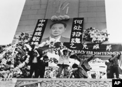 中国学生在北京天安门广场上的人民英雄纪念碑前展示胡耀邦像和“民主之光耀邦”等标语(1989年4月19日)