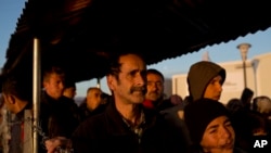 在希腊与马其顿的边界上的一个难民营里,叙利亚难民排队领取食物。(2016年2月25日)